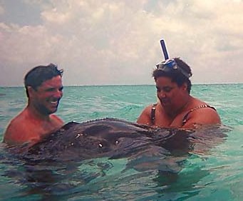 Captain helps Kasey hold a stingray in the sea